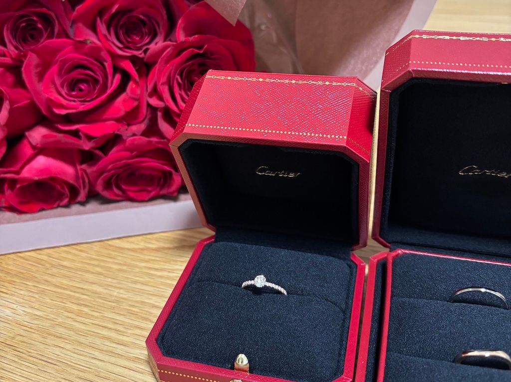 Beautiful red roses bouquet with elegant Cartier engagement and wedding ring boxes, symbolizing their love and commitment
